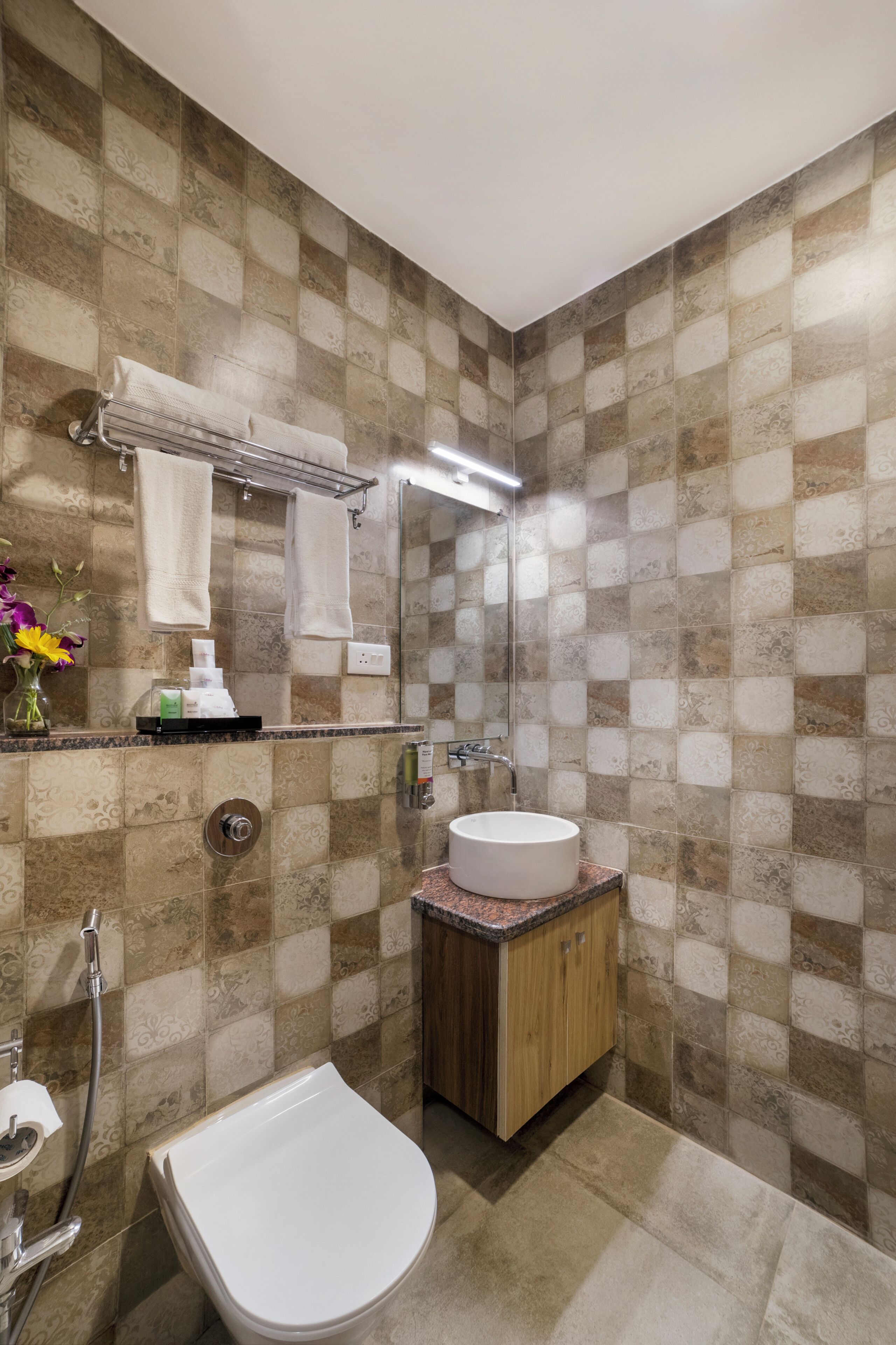 A bathroom with patterned tiles, a sink, a toilet, a towel rack, and a mirror.