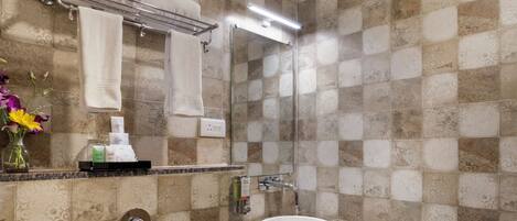 A bathroom with patterned tiles, a sink, a toilet, a towel rack, and a mirror.