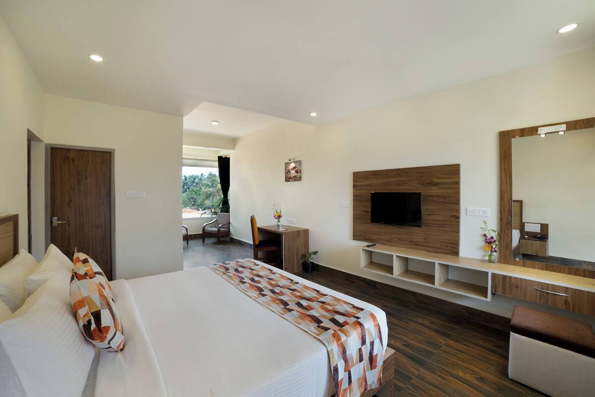 Quarto de hotel moderno com uma cama grande, uma escrivaninha, uma TV e um espelho.