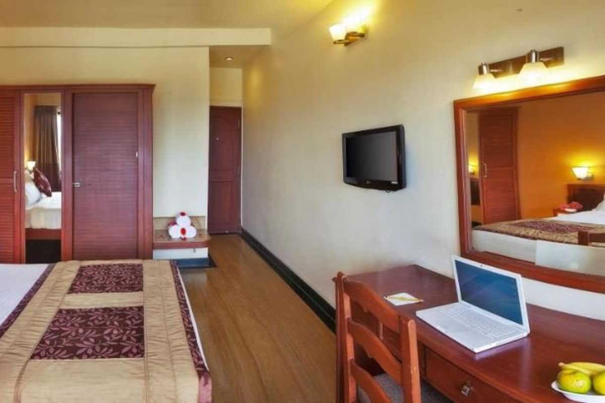 A hotel room with a bed, bedside table, desk, chair, and a television.