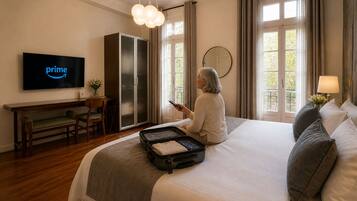 Une chambre d’hôtel comprenant un lit, un bureau, un téléviseur affichant le logo de Prime, une armoire et une fenêtre avec des rideaux.