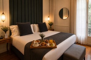 A hotel room with a large bed, bedside tables, a tray with breakfast items, and a view of greenery outside. - Duque Hotel Boutique & Spa (Buenos Aires)