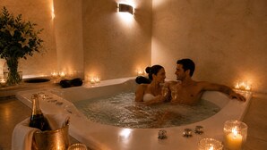A couple in a hot tub with candles, a bottle, and glasses. - Duque Hotel Boutique & Spa (Buenos Aires)