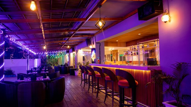 Espaço de bar com mobiliário de vime e balcão.