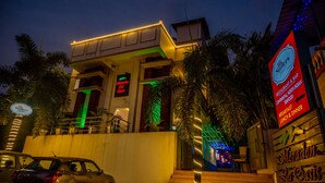 Um edifício com uma placa indicando o restaurante e bar 'Meraden La Oasis', apresentando uma escadaria e palmeiras.