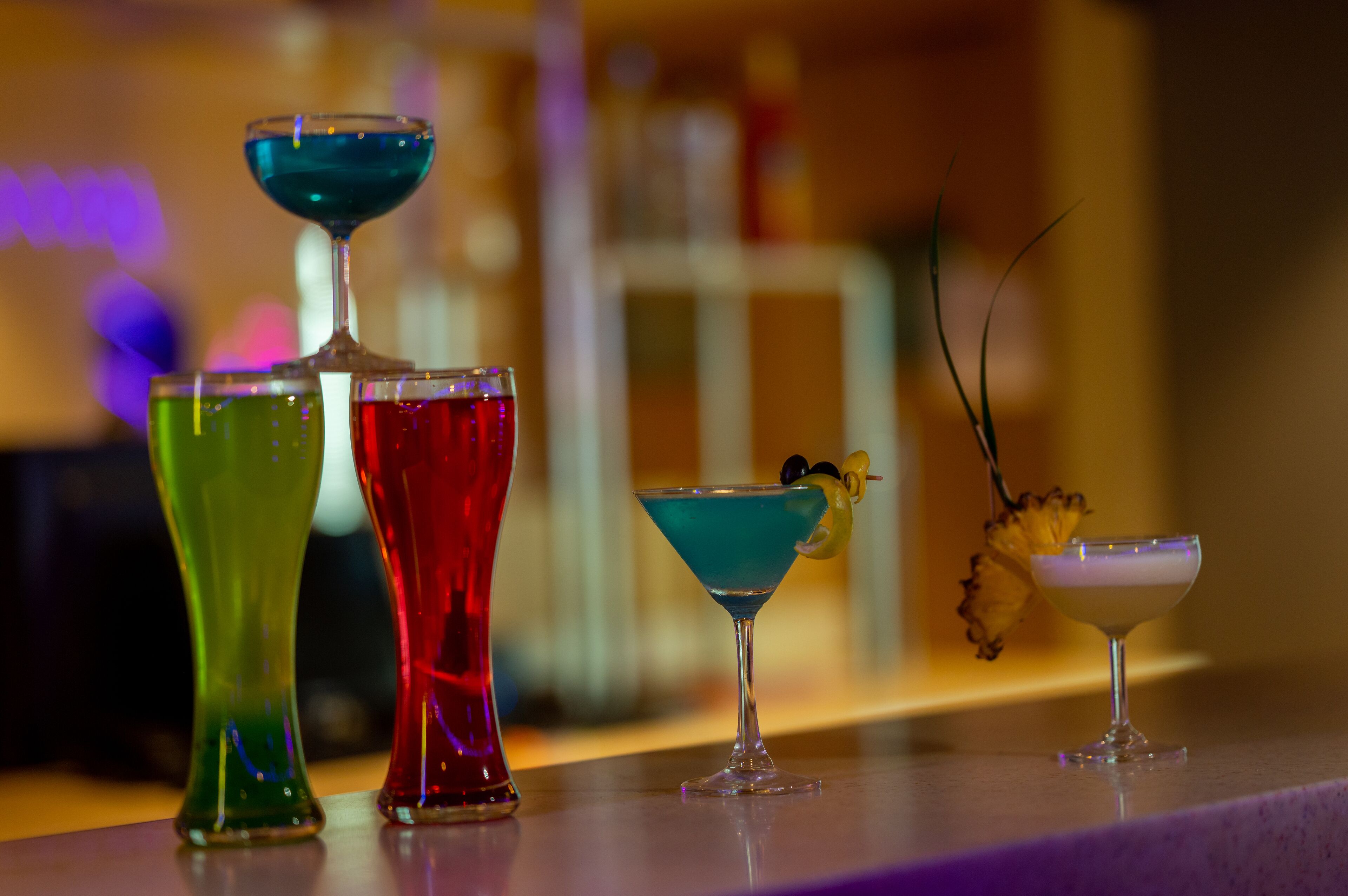 En bar med ett urval av färgglada drinkar serverade i martiniglas.
