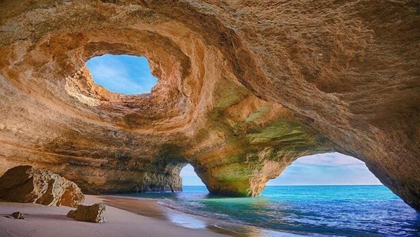 A natural rock formation with a circular opening, a sandy beach, and the sea. - Vale da Lapa Village Resort (Lagoa)