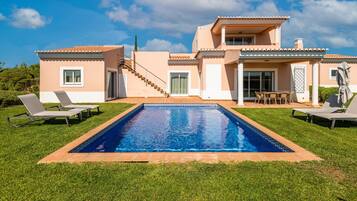 A two-story house with a swimming pool, outdoor seating, and a staircase leading to the upper floor.
