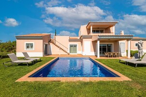 Una casa de dos pisos con piscina, zona de estar al aire libre y una escalera que conduce al piso superior.