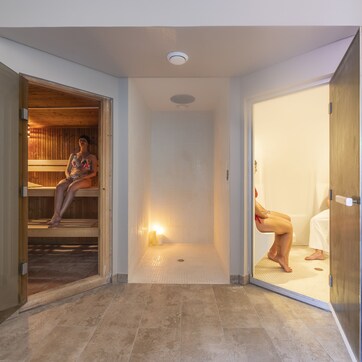 A sauna room with a wooden bench and a tiled floor.