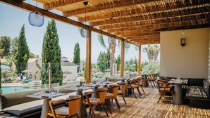 A restaurant with outdoor seating, wooden tables, and chairs, overlooking a pool and greenery. - Vale da Lapa Village Resort (Lagoa)