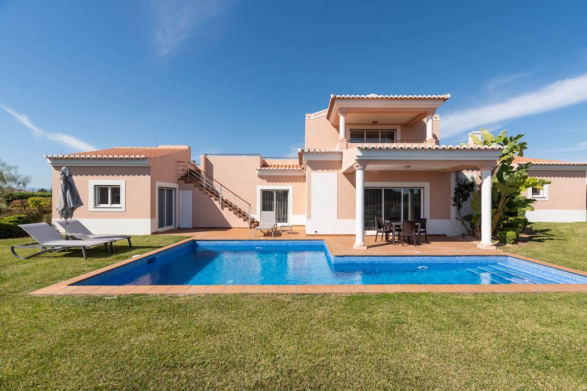 Une maison à deux étages dotée d’une piscine, d’un patio couvert et d’un escalier menant à l’étage supérieur.
