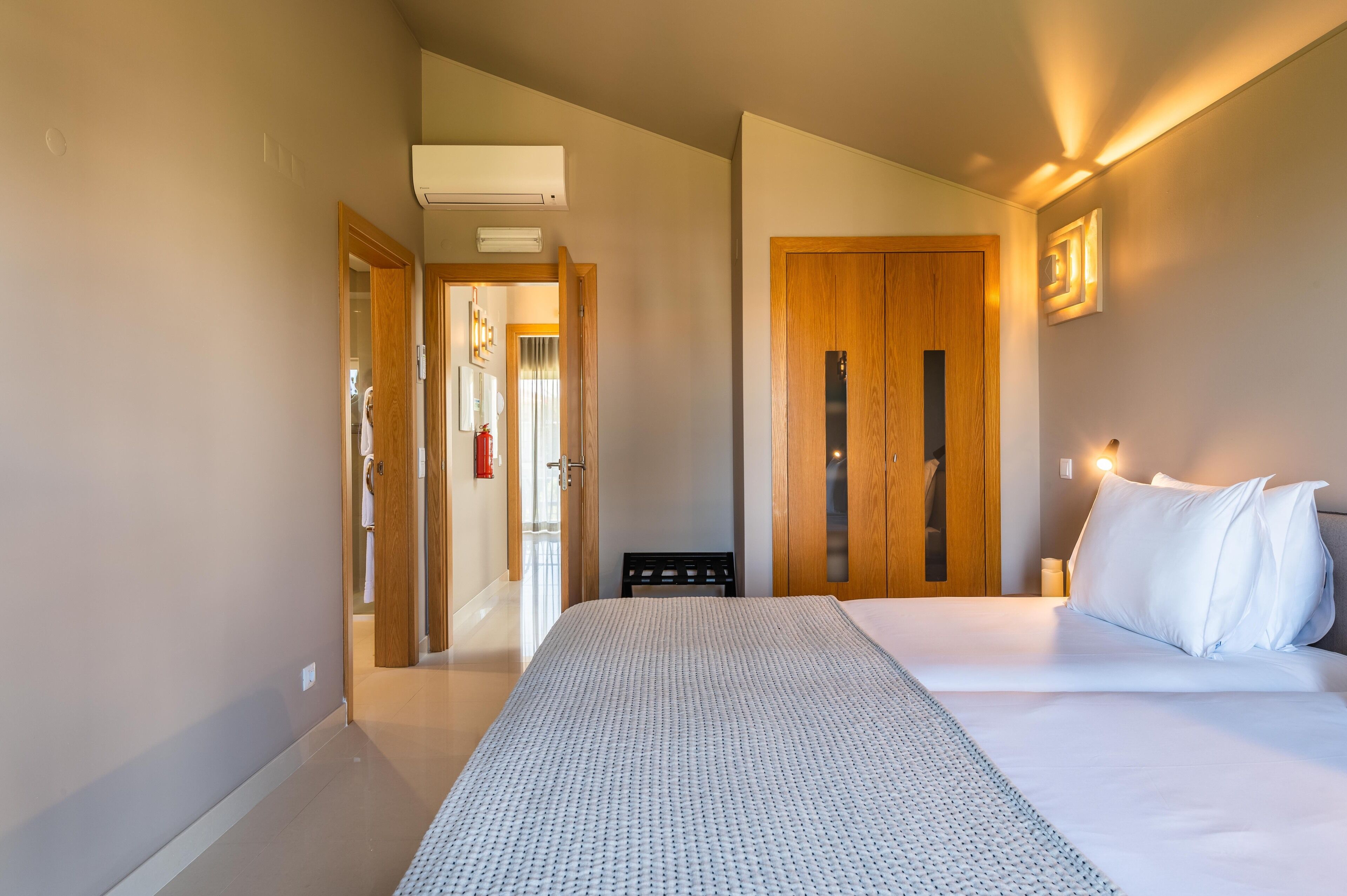 Una habitación de hotel con una cama, un armario y una puerta que da a un baño.
