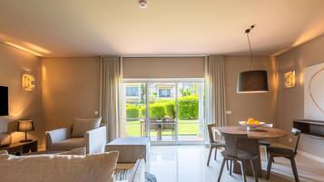 A modern living room with a sofa, a coffee table, and a dining area with chairs and a table.