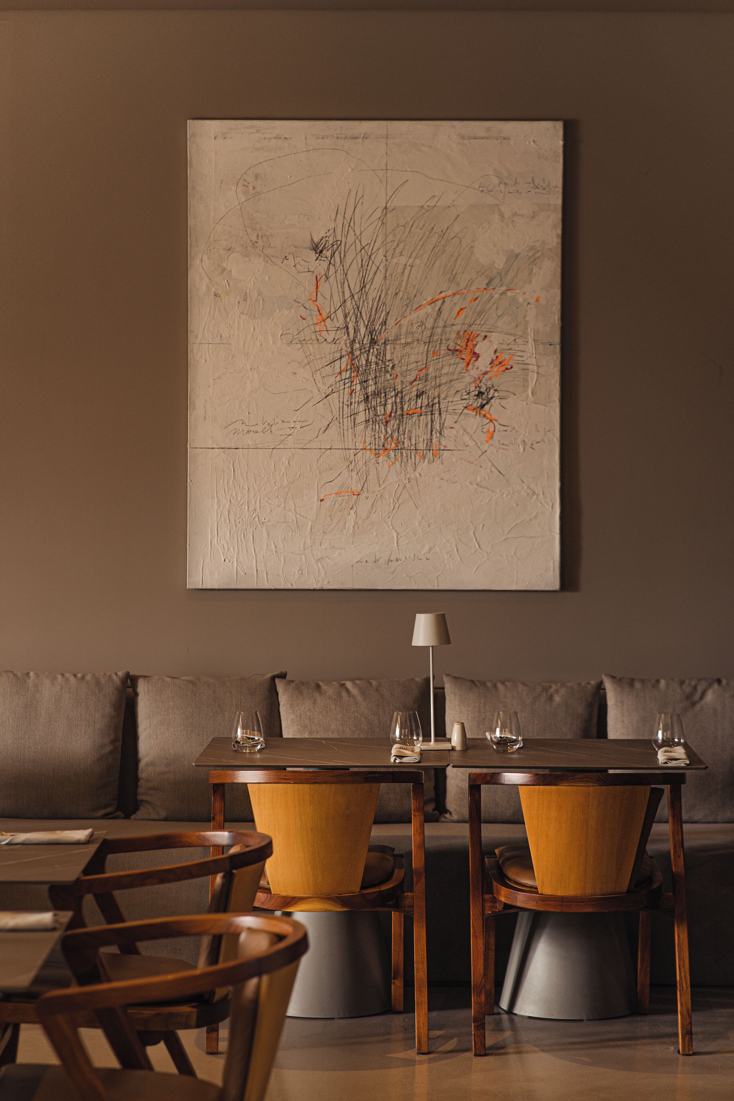 A dining area with a table and chairs, a sofa, and a large abstract painting on the wall.