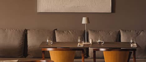 Un espace repas comprenant une table et des chaises, un canapé et un grand tableau abstrait accroché au mur.
