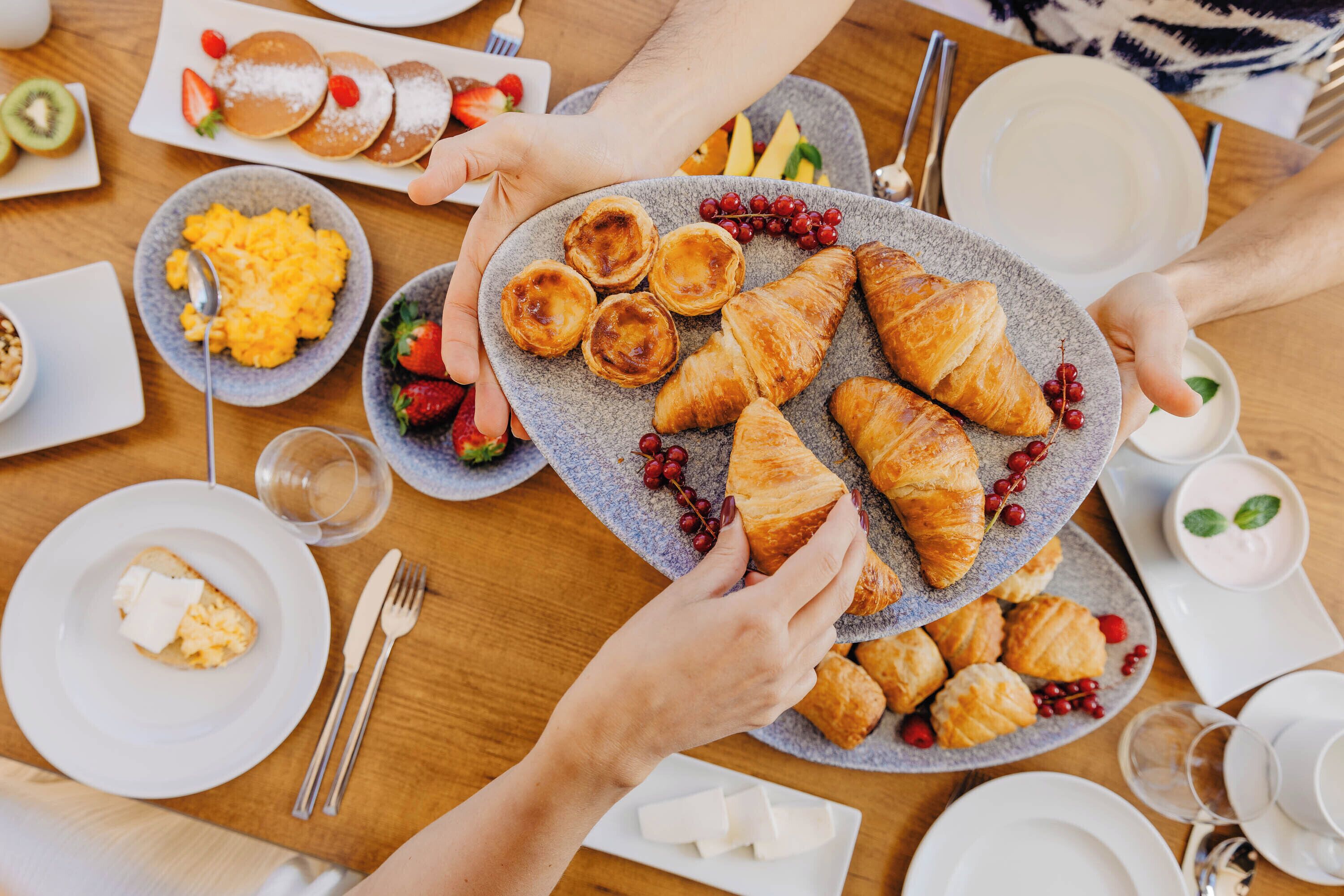 A breakfast setting with various dishes including pastries, scrambled eggs, and fruit.