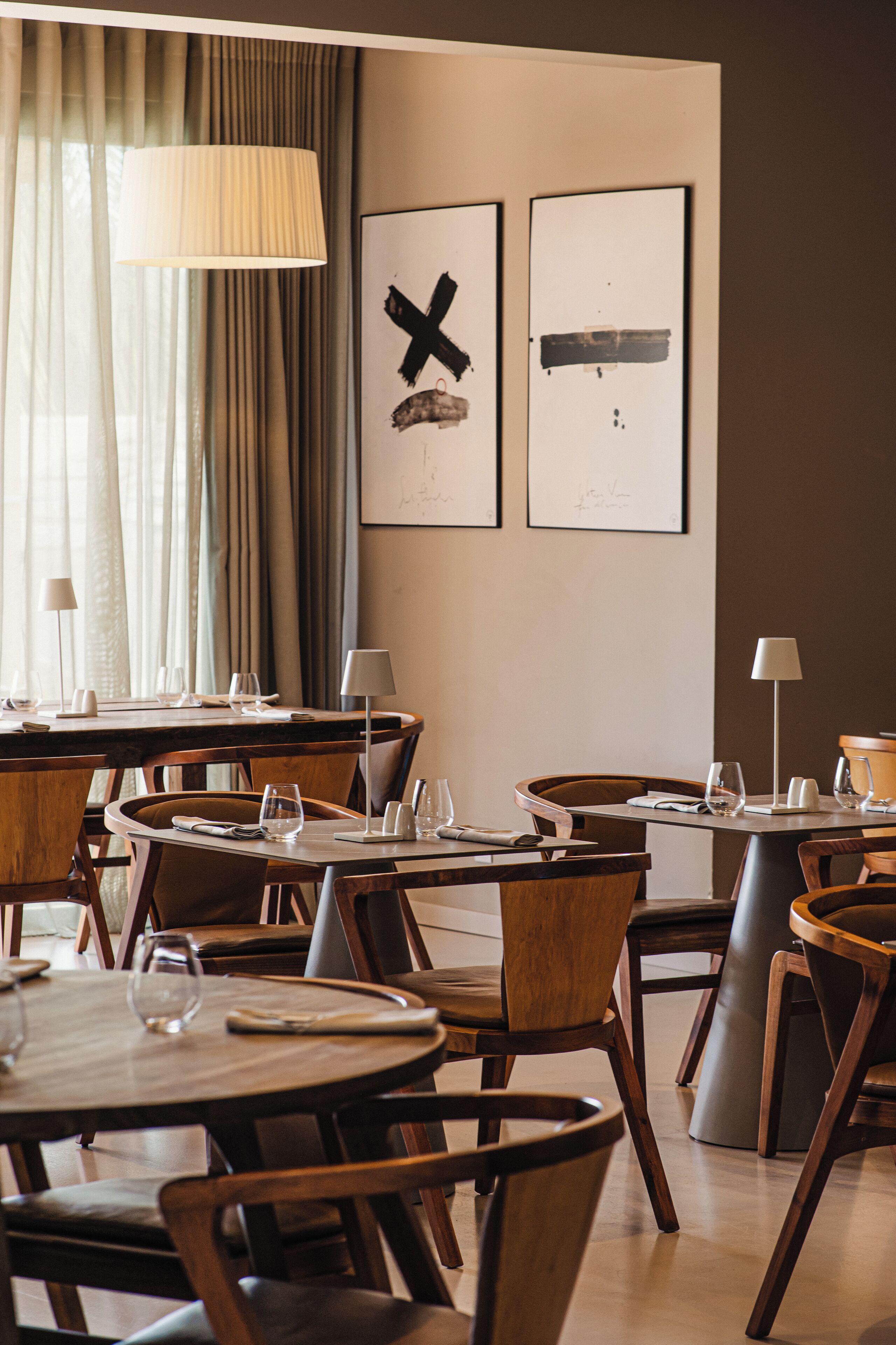 A dining area with wooden tables and chairs, arranged in a casual setting.