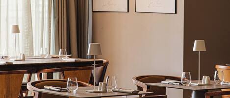 A dining area with wooden tables and chairs, arranged in a casual setting.