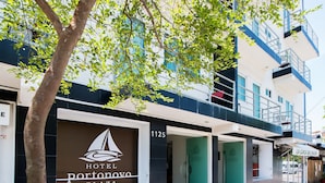 A hotel facade with a sailboat logo, a balcony, and a green door. - Hotel Portonovo Plaza Malecón (Puerto Vallarta)