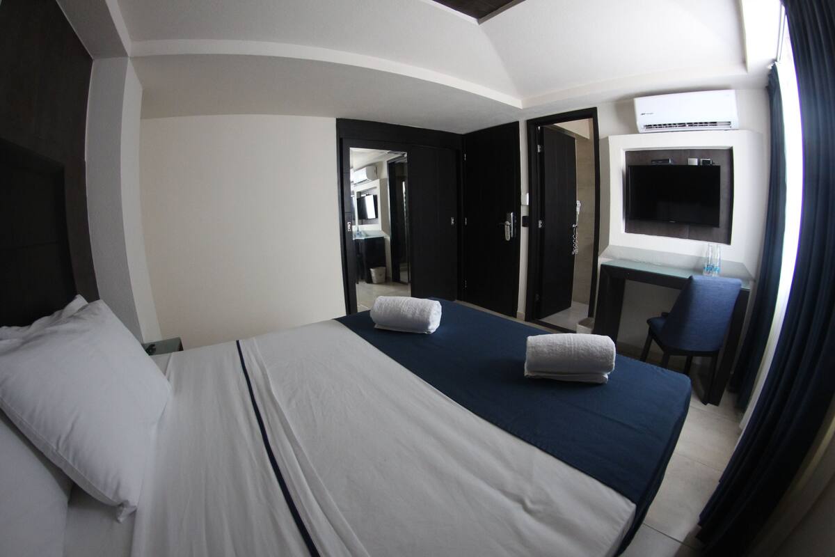 Habitación de hotel con cama, escritorio con televisor y una silla.