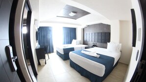 A modern hotel room with a large bed, a desk, and a separate seating area. - Hotel Portonovo Plaza Malecón (Puerto Vallarta)