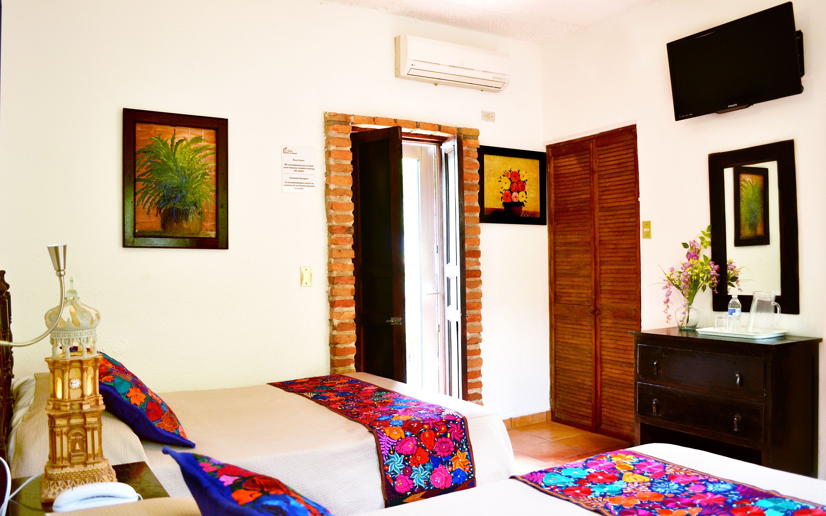 A hotel room with a bed, a bedside table, a lamp, a television, and a wardrobe.