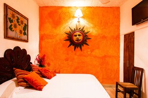 Una habitación con una cama, una silla de madera, un televisor de pared y una decoración de sol.