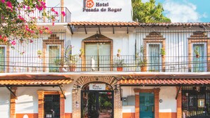 Hotel Posada de Roger with a traditional facade, a tiled roof, and balconies with potted plants.