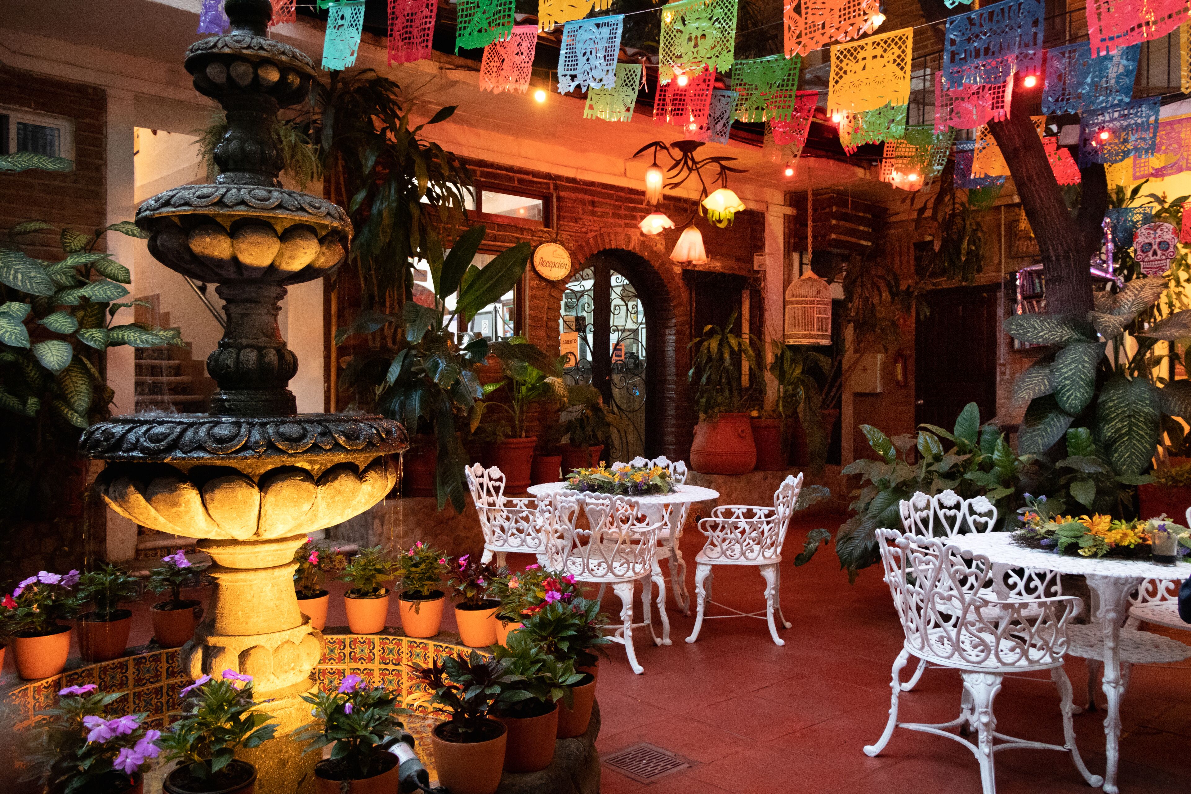 A courtyard with a fountain, potted plants, and outdoor seating.