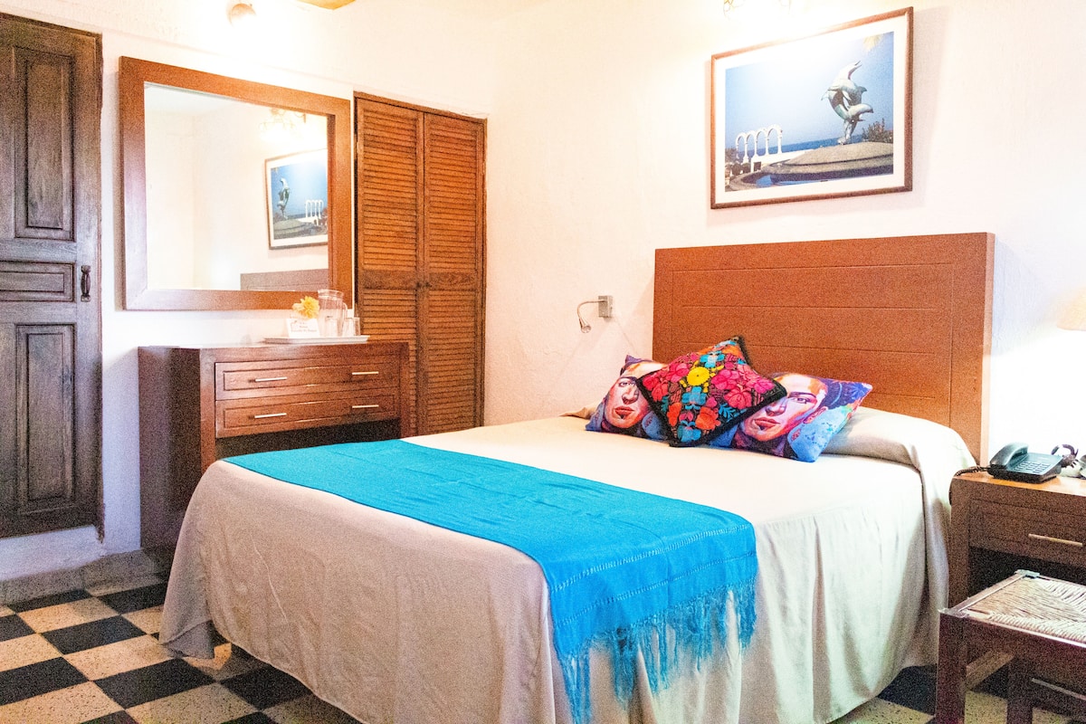 A bedroom with a bed, a dresser, a mirror, and a nightstand.
