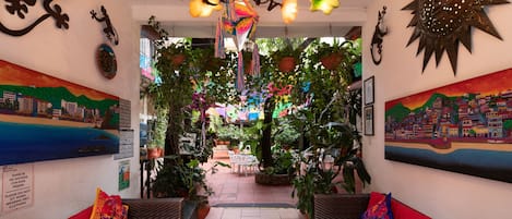 Un interior acogedor con un sofá rojo, muebles de mimbre y varias plantas.