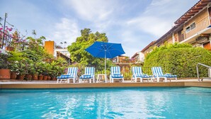 A swimming pool with blue and white striped lounge chairs and a blue umbrella.