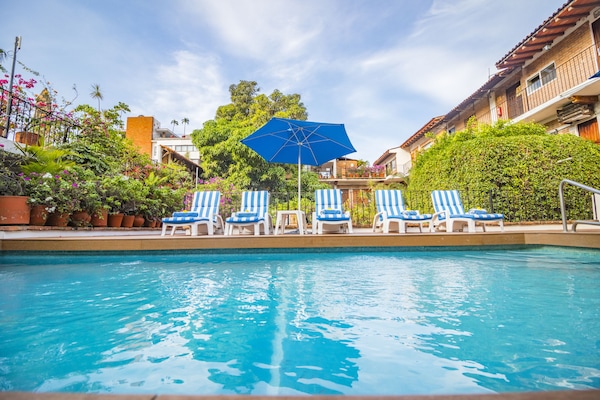 Una piscina al aire libre, sombrillas, tumbonas