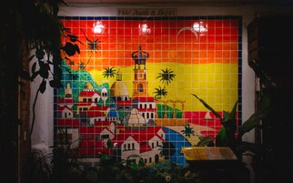 Un mural vibrante con un faro, palmeras y edificios, probablemente representando una escena de ciudad costera.