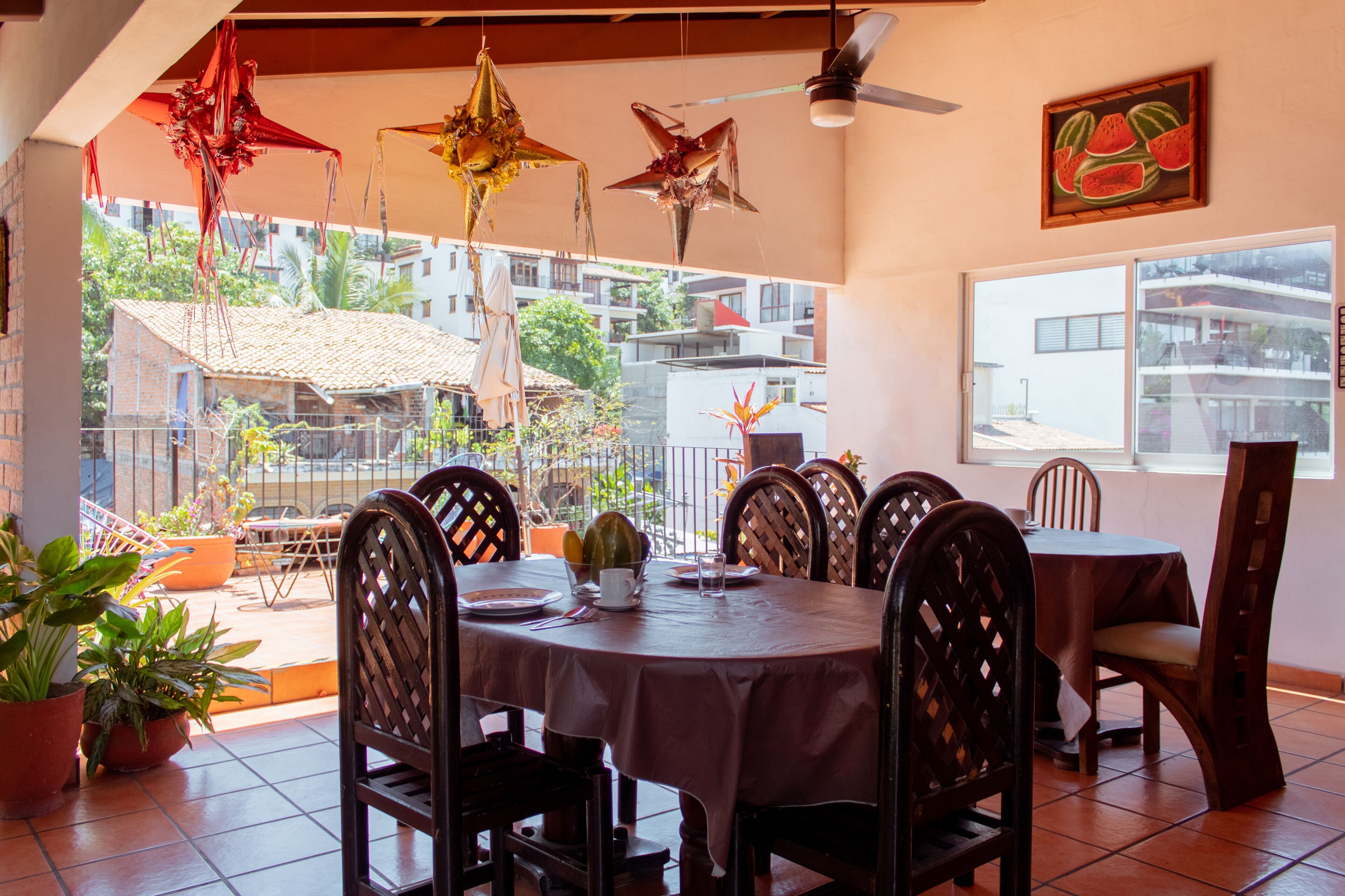 A dining area with a round table, chairs, potted plants, and hanging decorations.