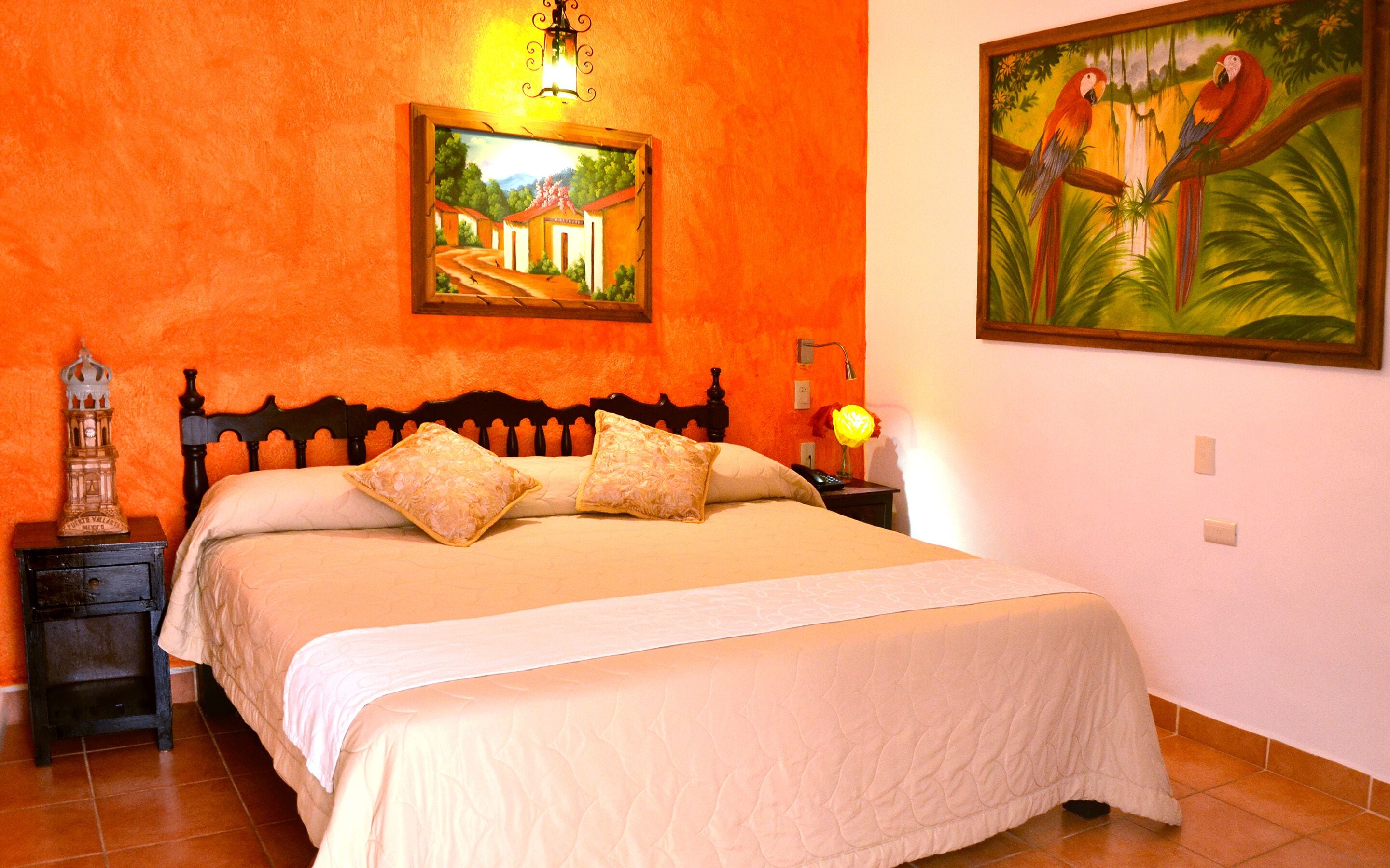 A bedroom with a bed, nightstands, a lamp, and two paintings on the wall.