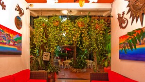 A hotel lobby with red sofas, a reception desk, and various potted plants.