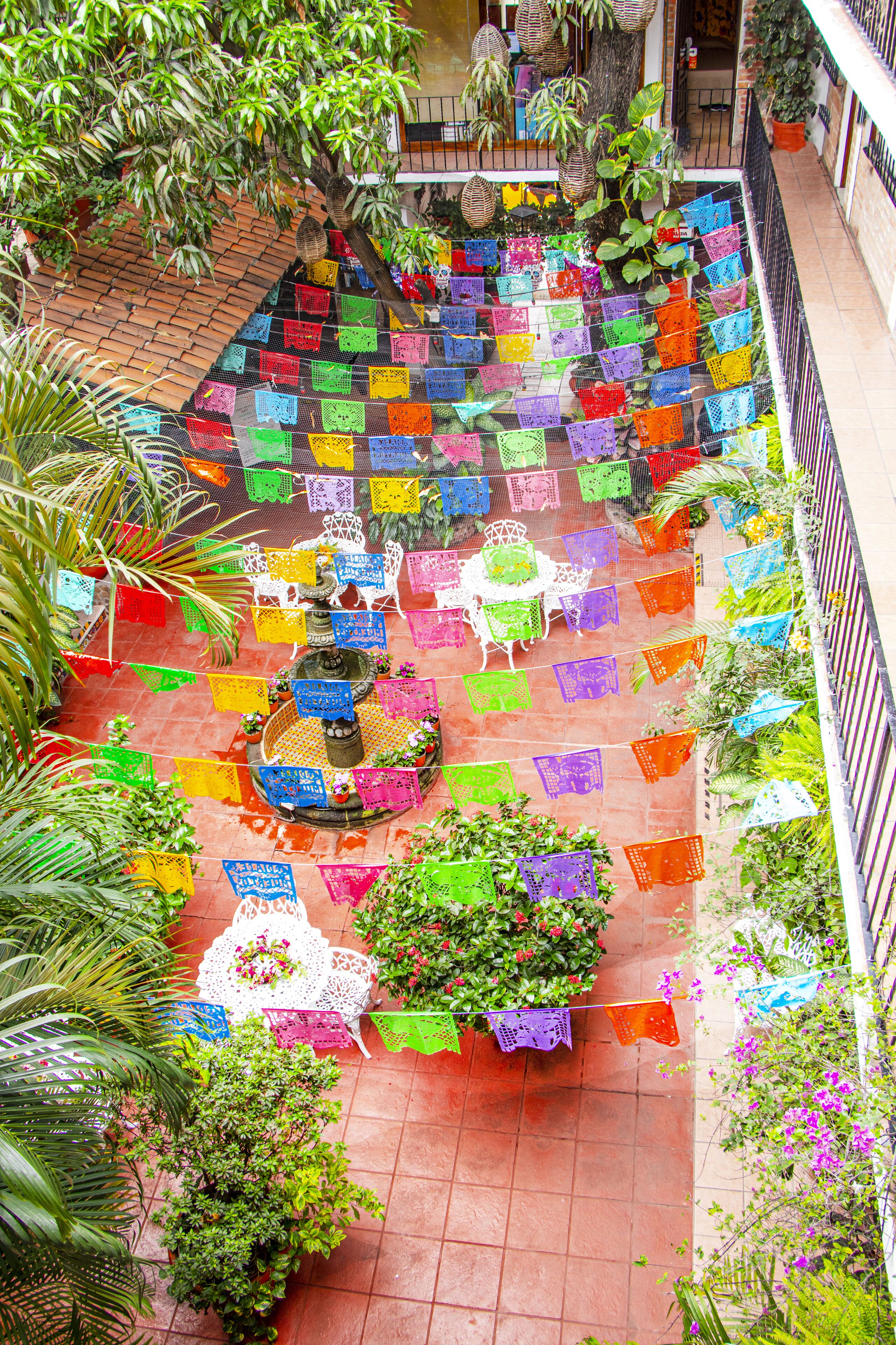 A courtyard with colorful flags, a fountain, and potted plants.