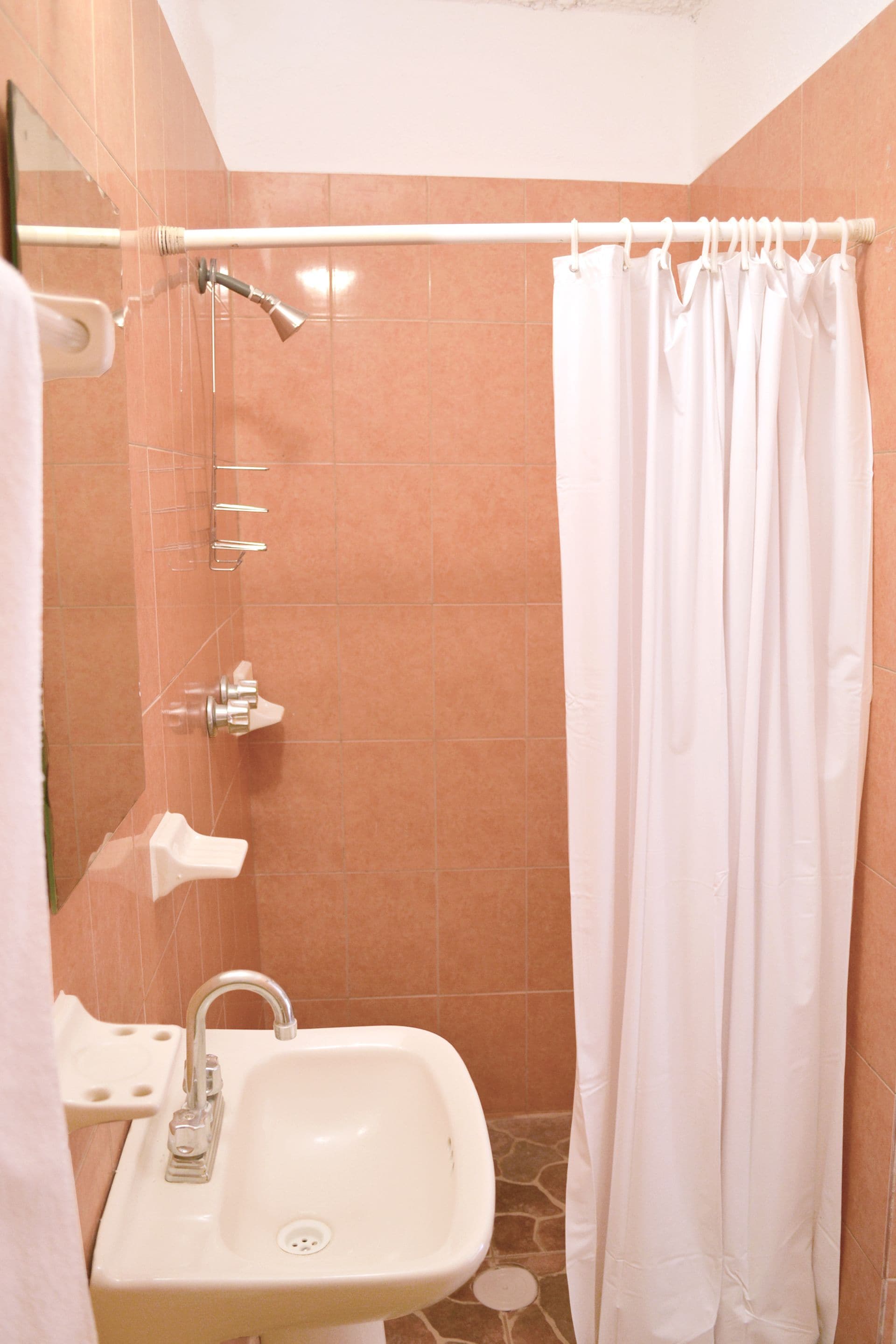 A bathroom with a white sink, a shower curtain, and a mirror.