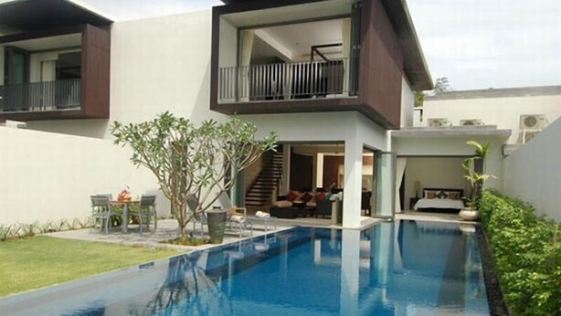 A modern two-story house with a swimming pool, a balcony, and a staircase leading to the upper floor.