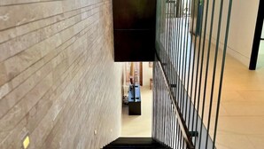 A modern interior with a staircase, wooden panel walls, and metal railings.