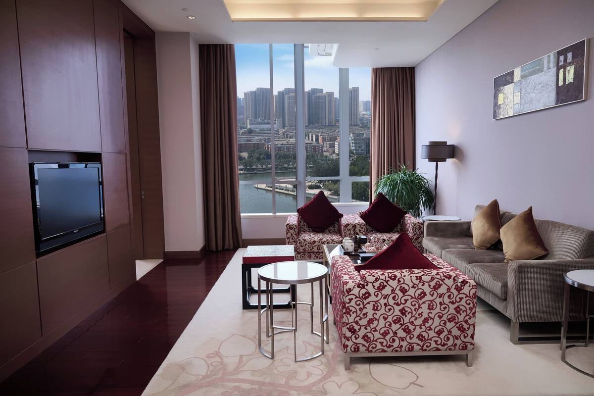 A modern living room with a city view, featuring a sofa set, a TV, and a coffee table.