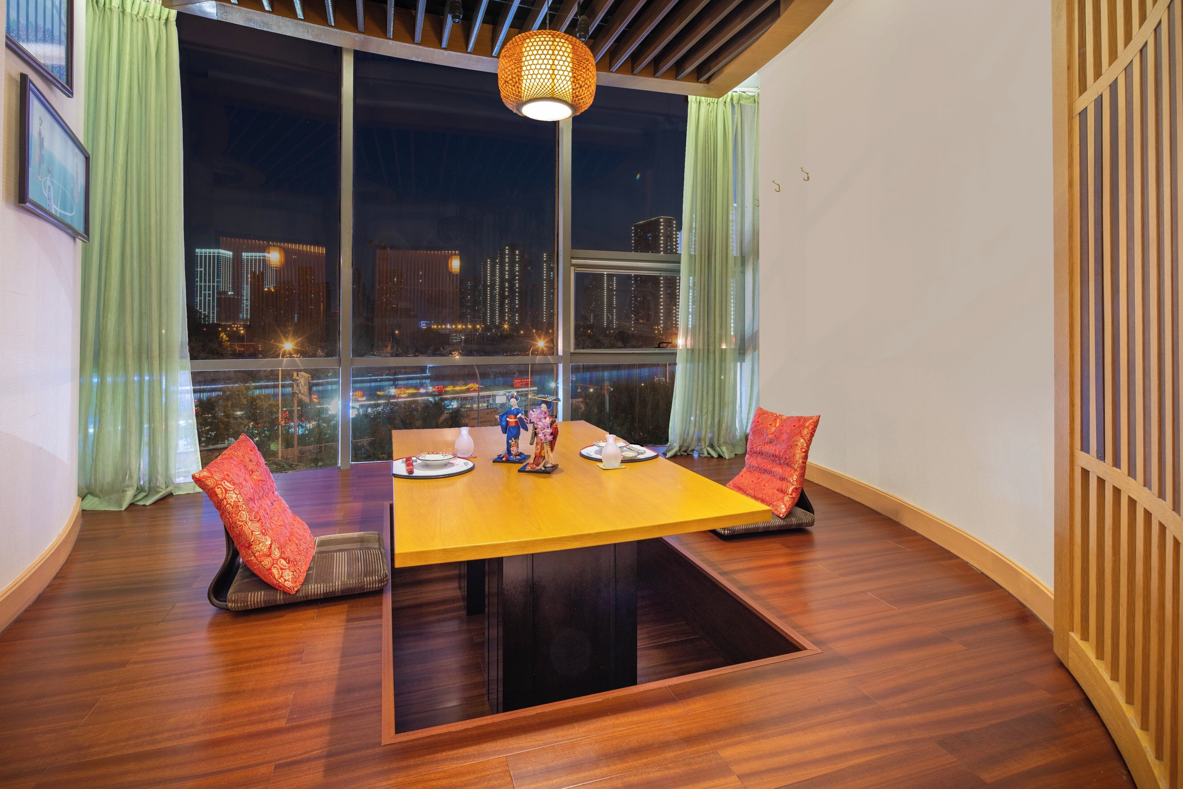 Un coin repas avec une table en bois, deux chaises et une vue sur le paysage urbain illuminé la nuit.