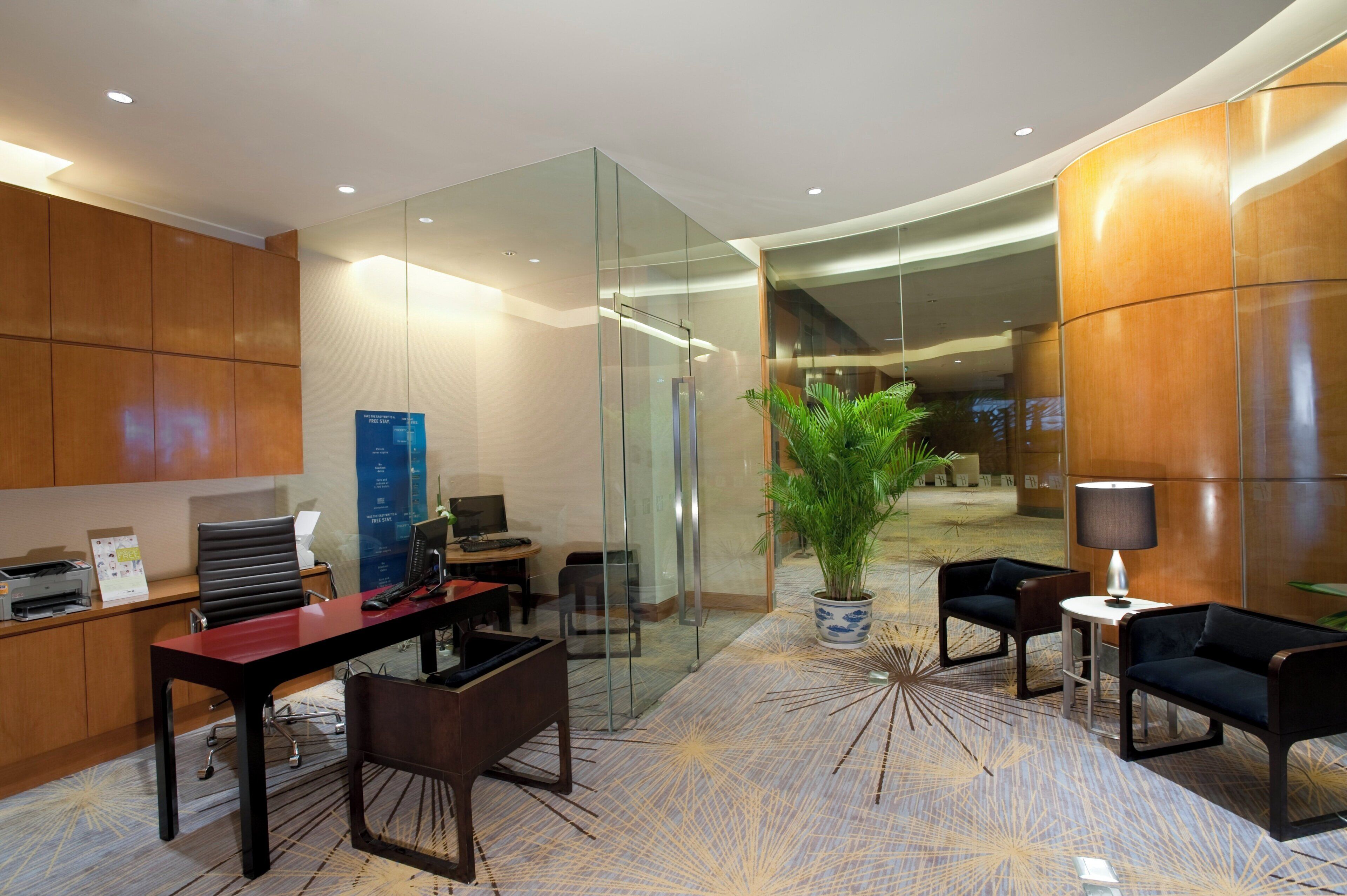 A modern office space with a reception desk, seating area, and a large potted plant.