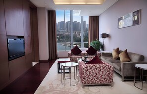 Una sala de estar moderna con vistas a la ciudad, que incluye un conjunto de sofás, un televisor y una mesa de centro.