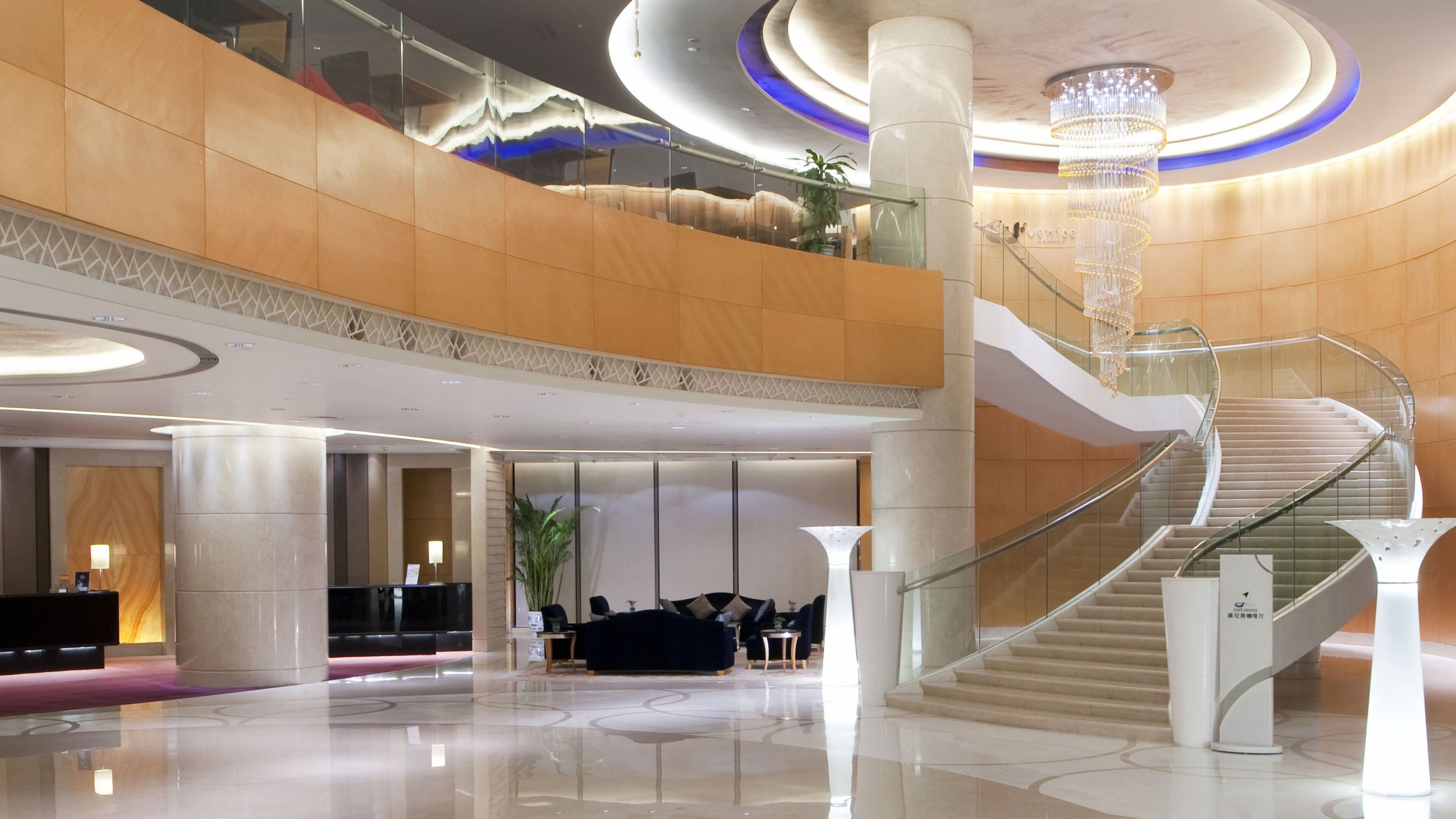 A spacious lobby with a grand staircase, a reception desk, and a seating area.