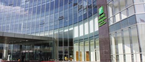 A modern building with a glass facade and a green sign indicating a Holiday Inn Express.