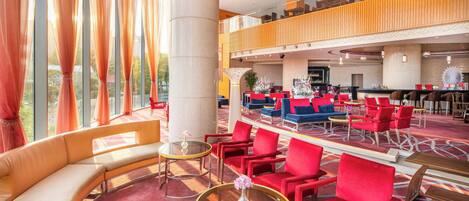 Un hall de hotel con zona de estar, mostrador de recepción y bar.
