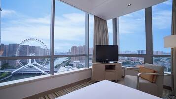 A hotel room with a large window offering a view of a Ferris wheel and cityscape.